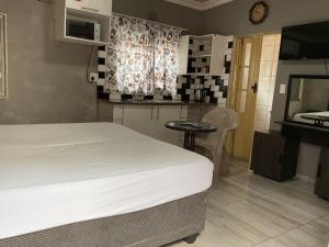 a bedroom with a bed and a table and a kitchen at northmead lodge in Benoni +24 photos