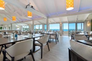 a dining room with tables and chairs and the ocean at Accessible Seaview Unit 3 in Waiheke Island