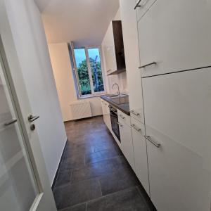 a kitchen with white cabinets and a tile floor at Heart of Essen in Essen +4 photos