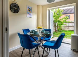 a dining room with a glass table and blue chairs at Sherbet House Stylish 3BR, 6 Guests Contractor Near NEC and Birmingham Airport Near NEC and Birmingham Airport in Water Orton