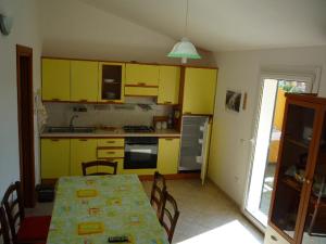 una cucina con armadi gialli e tavolo con sedie di Appartamento Valledoria Centro a Valledoria