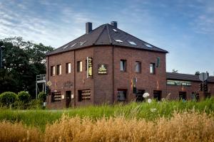 an old brick building in a field of tall grass at Hotel Omega in Moers