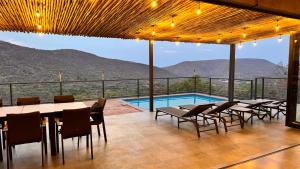 un restaurante con mesa, sillas y piscina en 19 on Idwala, Mabalingwe Game Reserve, en Bela-Bela