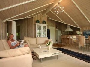 una mujer sentada en un sofá en una sala de estar en 6 person holiday home in Dronningmølle-By Traum, en Gilleleje