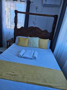 Cozy Breeze Apartment في مومباسا: منشفتان على سرير مع وسادتين