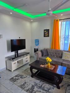 Cozy Breeze Apartment في مومباسا: غرفة معيشة مع أريكة وتلفزيون