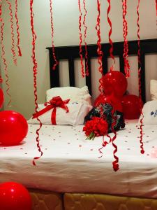 a bed with red balloons and a bunch of roses at Stay simple lodge in Lusaka