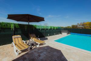 two chairs and an umbrella next to a swimming pool at Rustic Casa in Prijedor
