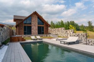 a pool with two chairs and a house at Heating pool villa with forest view, hot tube, cinema and PlayStation in Dilijan