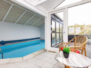 an indoor swimming pool with a table and a swimming pool at Seaside Wellness Retreat - By Traum Ferienwohnungen in Saltum +35 photos