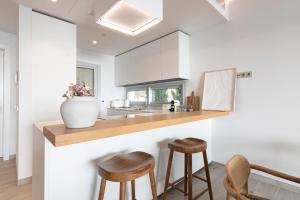 a kitchen with wooden counter stools and a vase at Mara's Apartments Higuerón - Azzurro Med Two Collection - Seaviews in Fuengirola