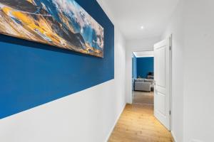 un tableau sur un mur bleu dans un couloir dans l'établissement Erholsame Wohnung mit Balkon und Einbauküche im Herzen Leipzigs, à Leipzig
