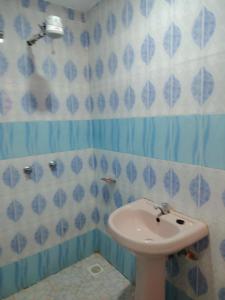 La salle de bains est pourvue d'un lavabo et de murs carrelés bleus et blancs. dans l'établissement Hephy Suites and BnB, à Nairobi