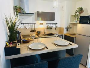 a kitchen with a table with two plates and wine glasses at Cocon urbain, appartement 4 personnes avec jardin à 2mn de Vannes, Golfe du Morbihan in Plescop