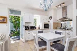 a kitchen with white cabinets and a table and chairs at Amanzi on Thesen Island - Knysna in Knysna