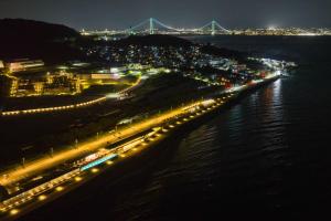 une ville illuminée la nuit avec un pont en arrière-plan dans l'établissement Aquaignis Awaji Island TRAILER PARK, à Awaji