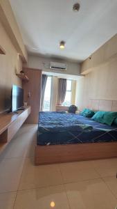 una camera da letto con un letto grande e una televisione di Apartemen Anderson PTC surabaya by staycation 28 a Surabaya