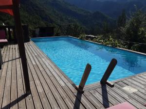 a swimming pool on a wooden deck with mountains in the background at Gallinette, joli appartement avec terrasse privative in Rigaud