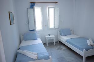 a white room with two beds and two windows at kikis apartments in Drios