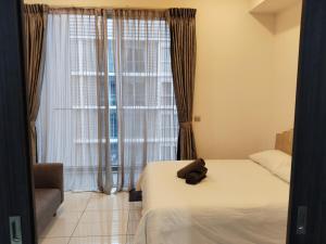 a teddy bear laying on a bed in front of a window at Condo in Jalan Ampang- near KLCC IJN Gleneagles HKL TRX in Kuala Lumpur