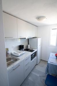 a white kitchen with a sink and a refrigerator at kikis apartment a veranda dream in Drios +7 photos