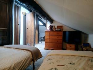 a bedroom with two beds and a dresser with a television at 90 m2, 3 chambres, coeur de village, 10 mns des pistes, navette gratuite in Bolquere Pyrenees 2000