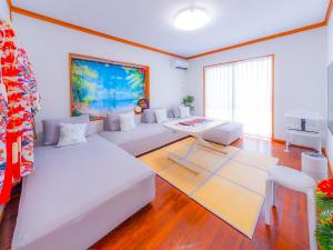 a living room with a white couch and a table at 琉球乃風-プチョヘンザ- in Uruma