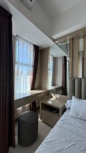 una camera da letto con un letto, una scrivania e uno specchio di Anderson Benson Pakuwon mall Daily by Sty a Surabaya