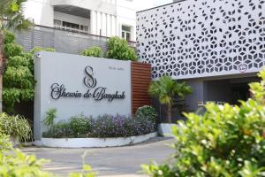 a sign in front of a building with purple flowers at Shewin de Bangkok in Ban Bang Bamru