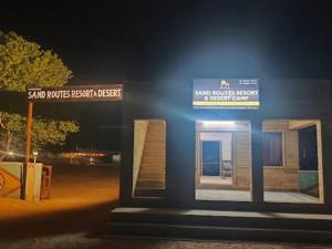 ein Schild an der Seite eines Gebäudes in der Nacht in der Unterkunft Sand Routes Resort & Desert Camp in Sām