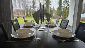 a table with plates and glasses on top of it at Eco-friendly stay with hot tub & panorama view in Oulu
