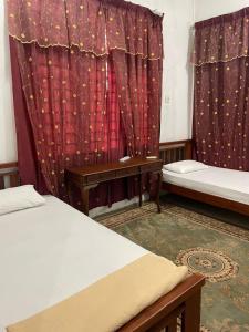 a room with two beds and red curtains at Damaisari Tawang in Bachok