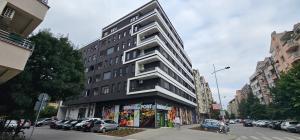 a tall building on a city street with parked cars at Premier Nova Residence in Novi Sad