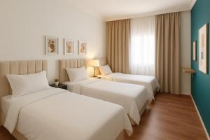 a hotel room with two beds and a window at شقة 7 هادئة بتصميم انيق ثلاث غرف ودخول ذاتي in Al Khobar