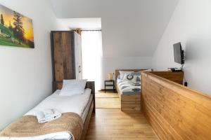a bedroom with two beds and a tv on a wall at Apartamenty u Jakubika in Krynica Zdrój