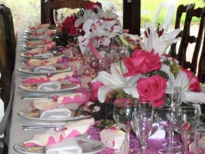 een lange tafel met roze en witte bloemen en wijnglazen bij Auberge d'Andaines in La Ferté-Macé
