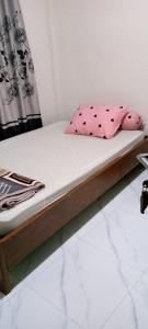 AmbaritaにあるDavid Silalahiの木製のフレームとピンクの枕が付いたベッド