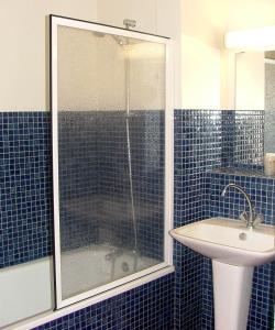 a blue tiled bathroom with a shower and a sink at Auberge d'Andaines in La Ferté-Macé