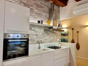 a white kitchen with a sink and a stove at Casa Baldi | Centro storico di Rimini in Rimini