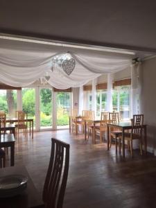 uma sala de jantar com mesas, cadeiras e janelas em Leeford Place Hotel em Battle