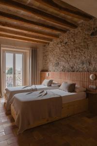 a bedroom with two beds and a stone wall at Casa boutique a Vilamacolum in Vilamacolum