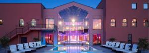 a building with a pool in front of a building with white chairs at Le Marrakech Boutique Hotel in Kleinblittersdorf
