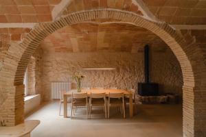 a dining room with a table and a brick wall at Casa boutique a Vilamacolum in Vilamacolum