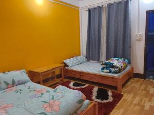 a small room with two beds and a window at Eton Homestay in Dirang Dzong