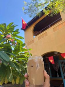 une personne tenant un verre avec un bâton dedans dans l'établissement Tre Hội An Heritage Inspired Homestay & Café, à Thanh Ðông (1)
