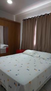a bedroom with a large bed with a white comforter at Apart 2 Ilha dos Araújos 2 quartos e completo 114 m2 in Governador Valadares