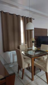 a dining room with a glass table and chairs at Apart 2 Ilha dos Araújos 2 quartos e completo 114 m2 in Governador Valadares