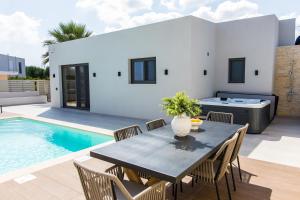a patio with a table and chairs and a swimming pool at Infinity Palm Villa in Stavros