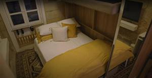 a small bed with yellow pillows in a small room at Sand - Rooftop Views, Wine Cellar & Espresso in Senglea