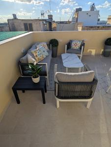a patio with a couch and tables on a balcony at Sand - Rooftop Views, Wine Cellar & Espresso in Senglea